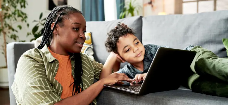 Oedolyn a phlentyn yn edrych ar laptop